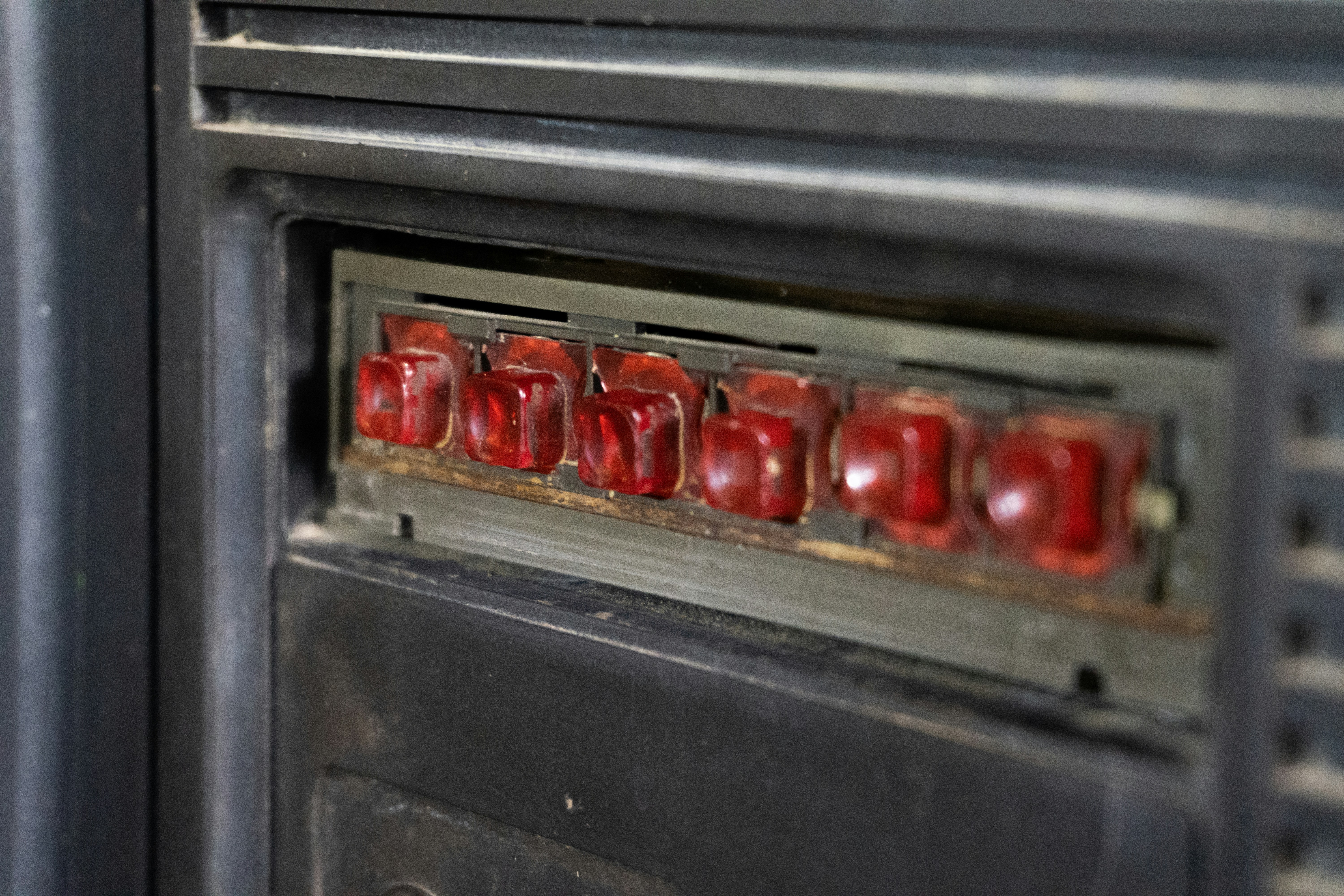Row of red illuminated buttons on a vintage device.