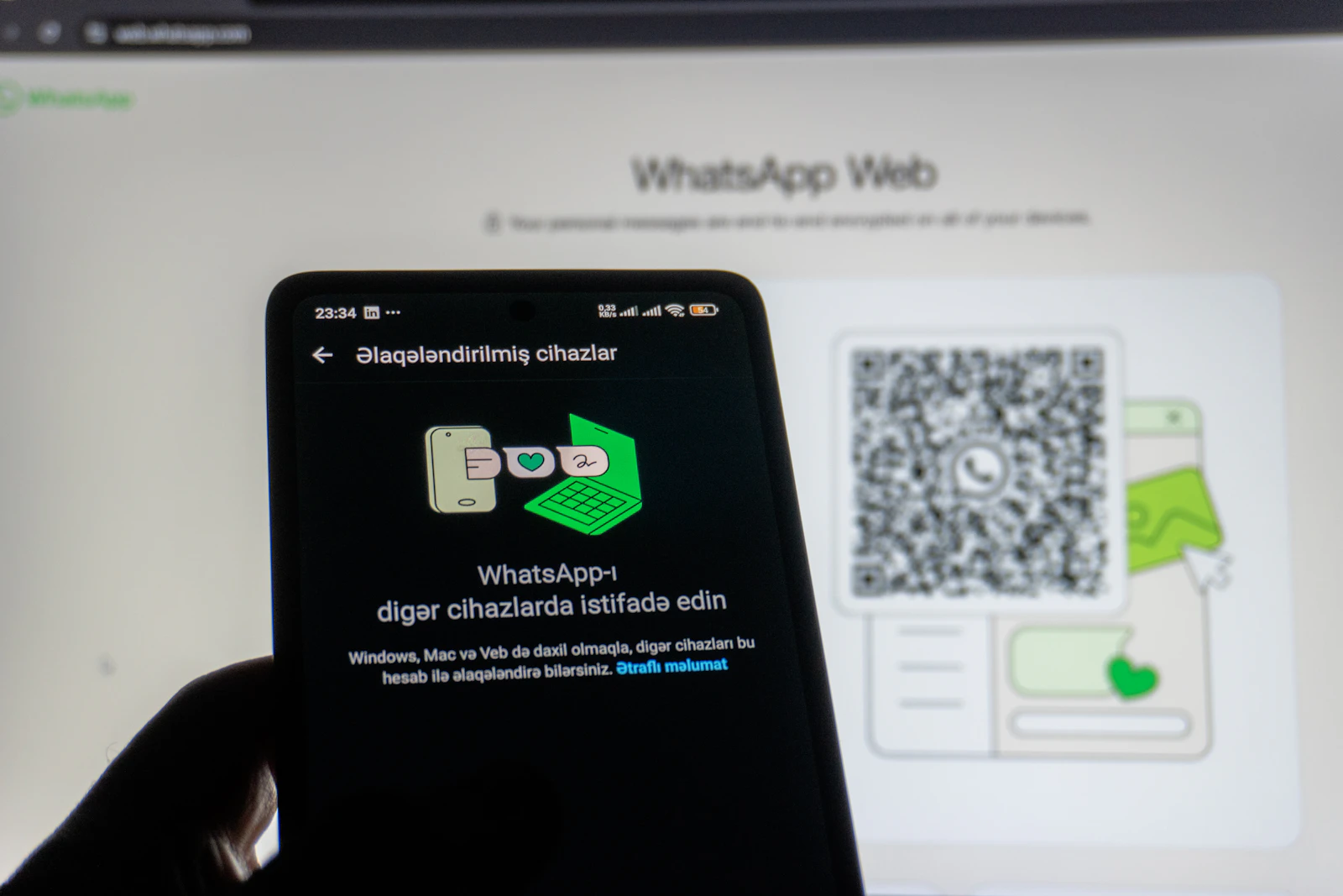 Phone held in front of a QR code on a computer screen, the scan used to set up an authenticator app
