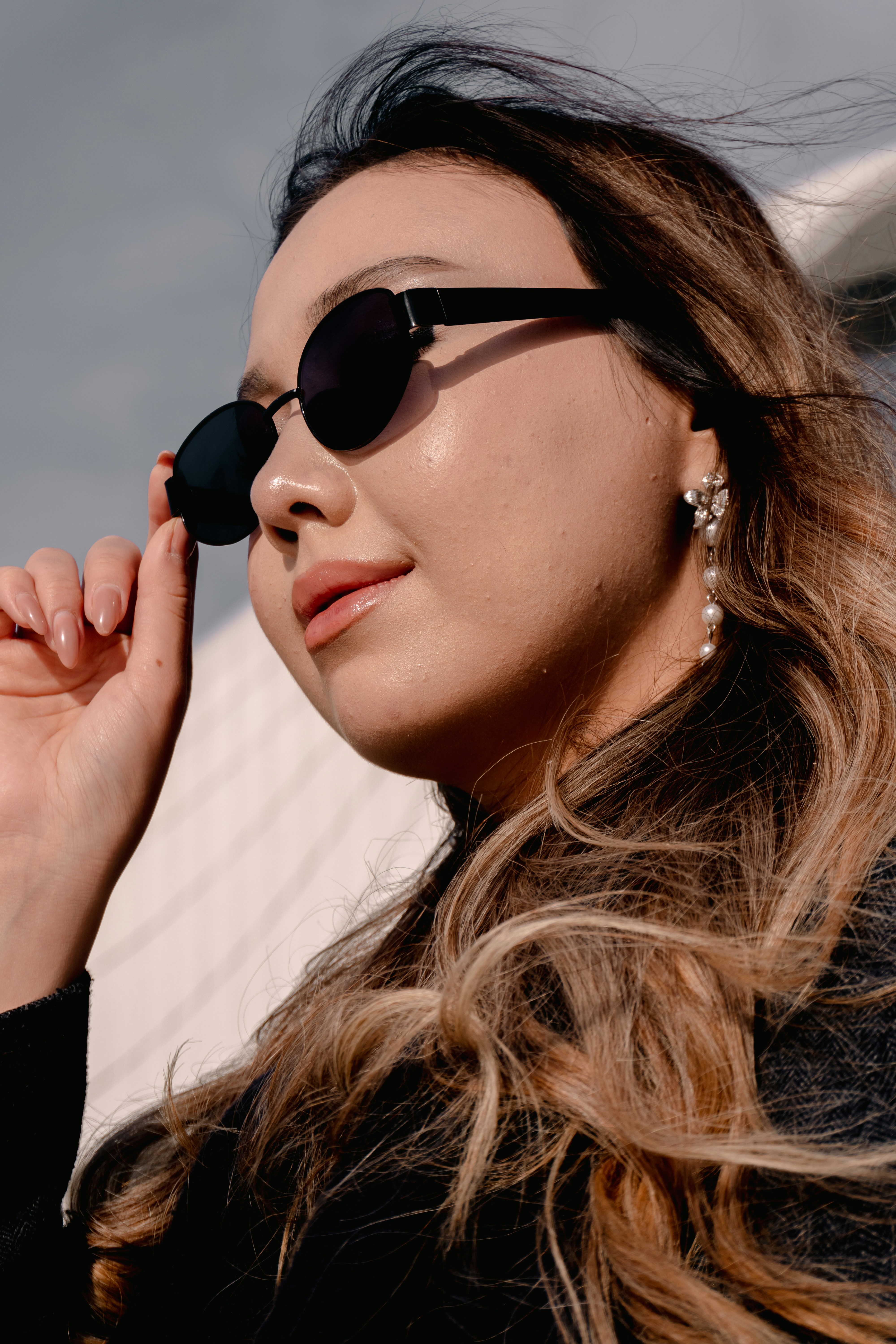 Junge Frau mit Sonnenbrille und langen gewellten Haaren