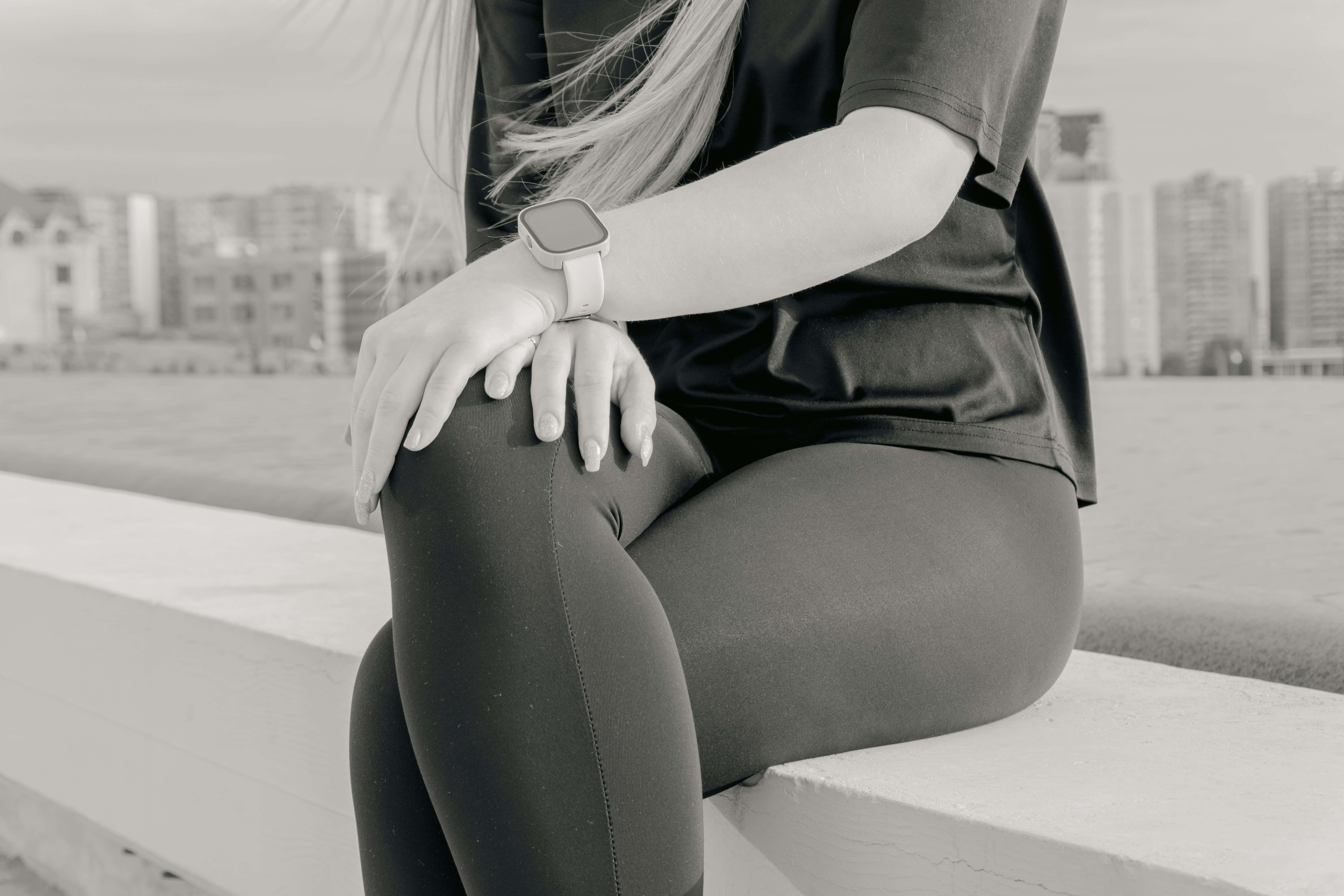 Woman in athletic wear sitting outdoors with city skyline.