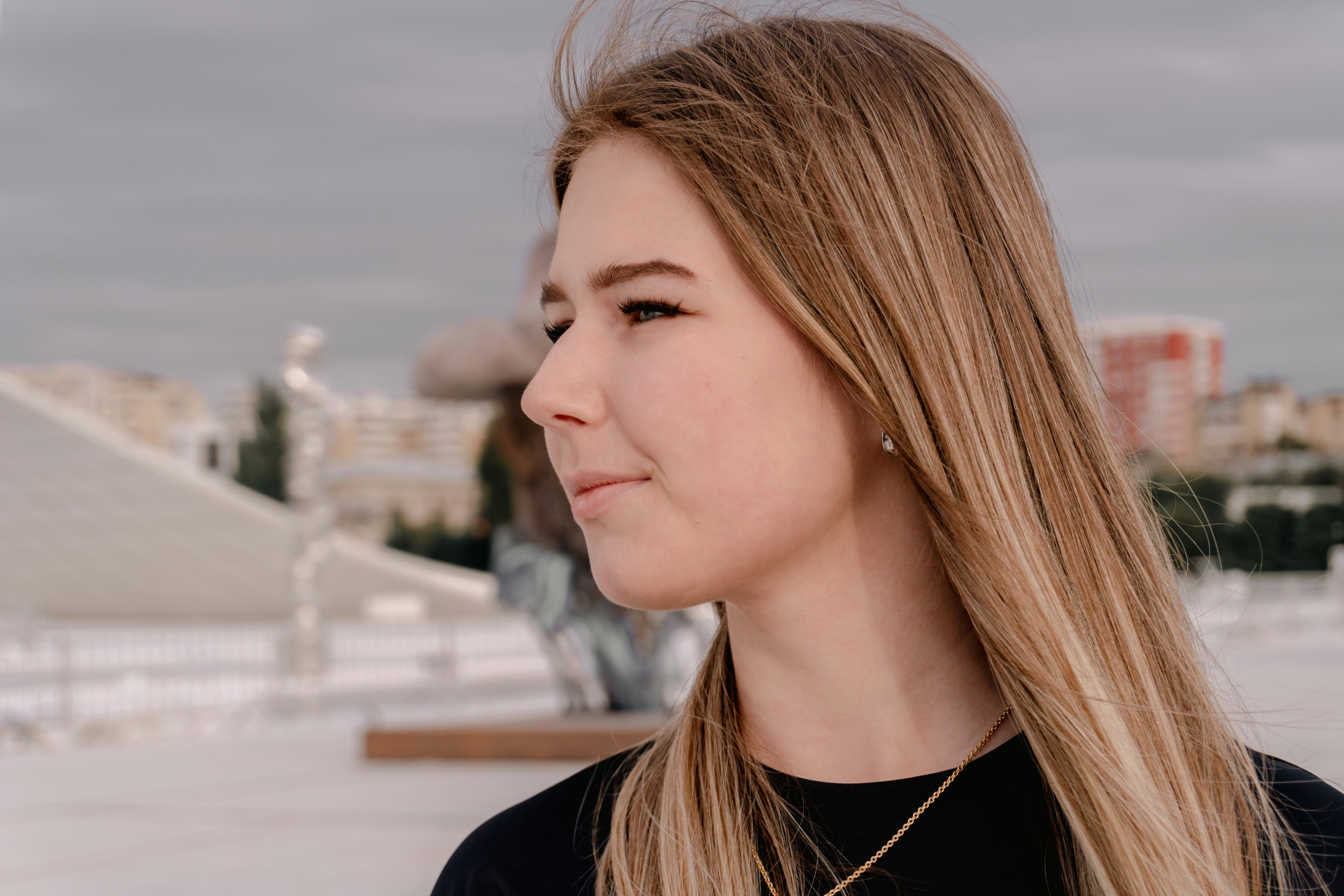 Young woman with blonde hair looking sideways outdoors