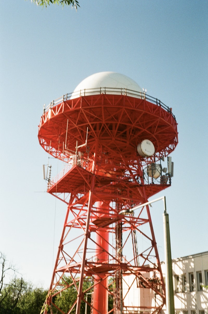 Red radar tower with white dome against sky