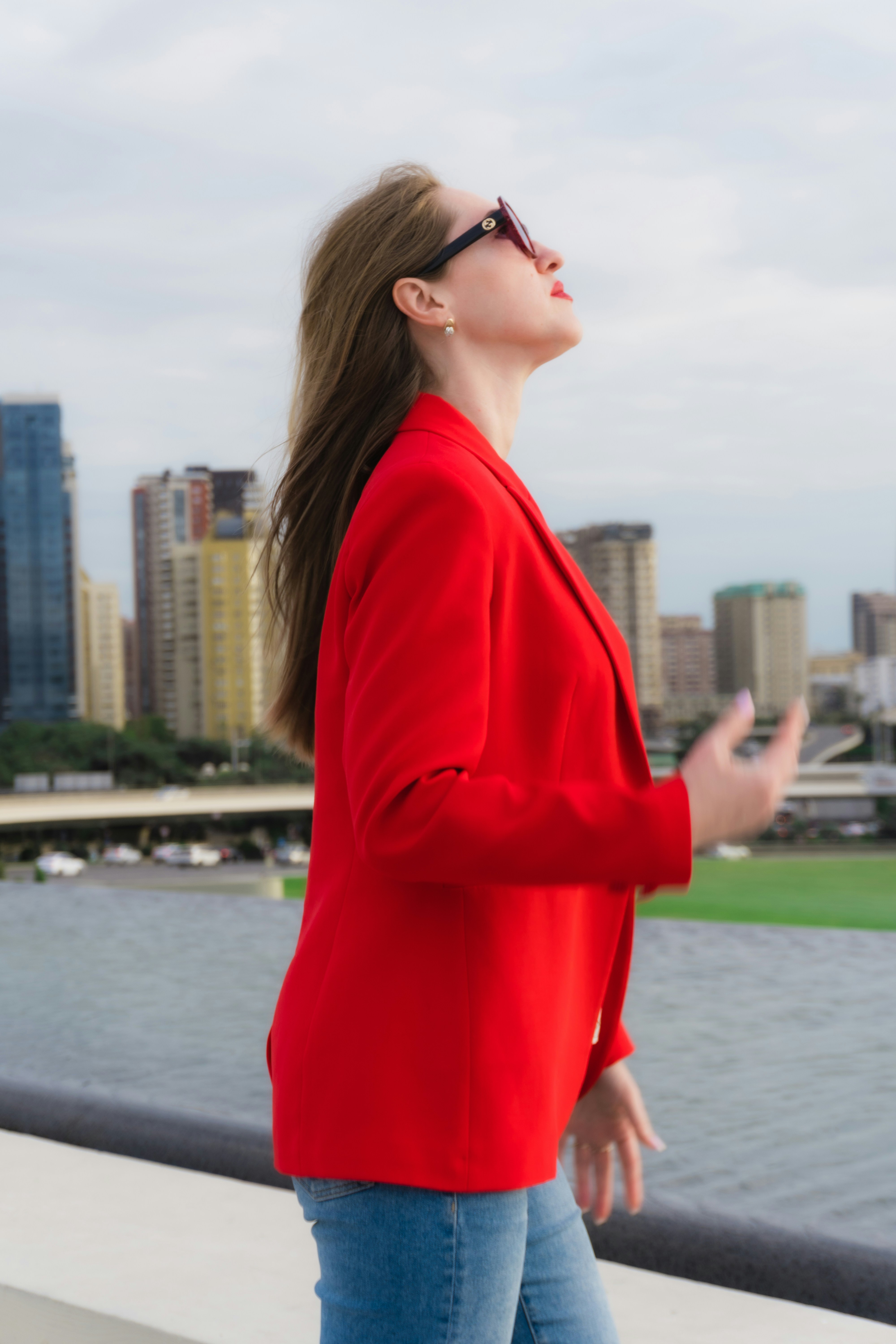 Woman in red jacket with sunglasses looking up.