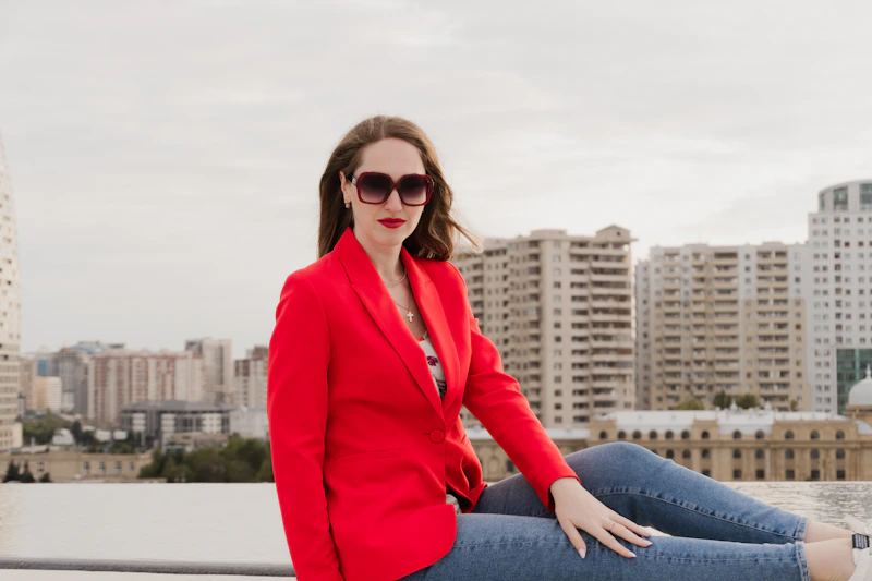 Sugar Mommy colombiana en blazer rojo sentada en azotea con vistas a la ciudad