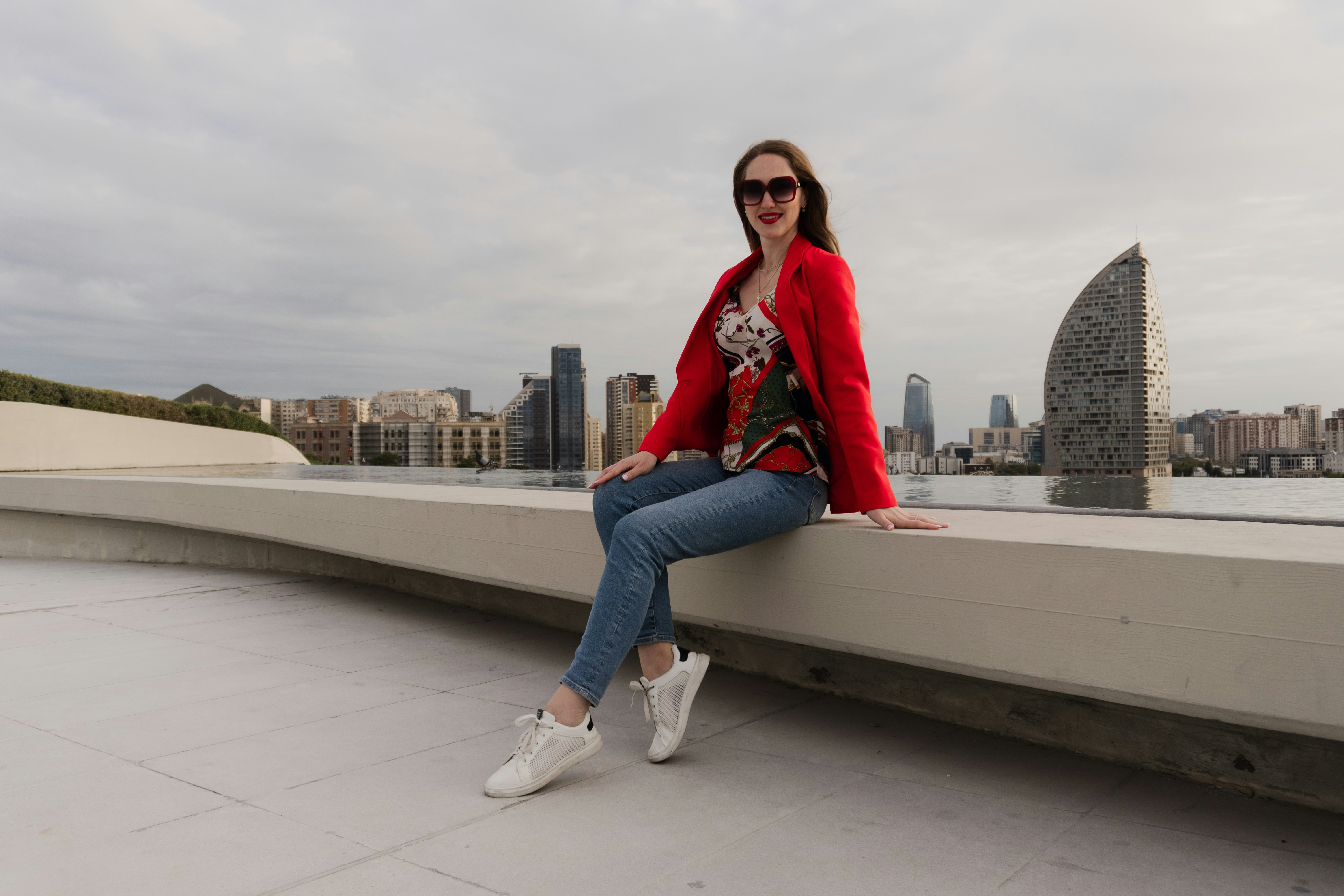 Woman in red jacket sitting with cityscape background