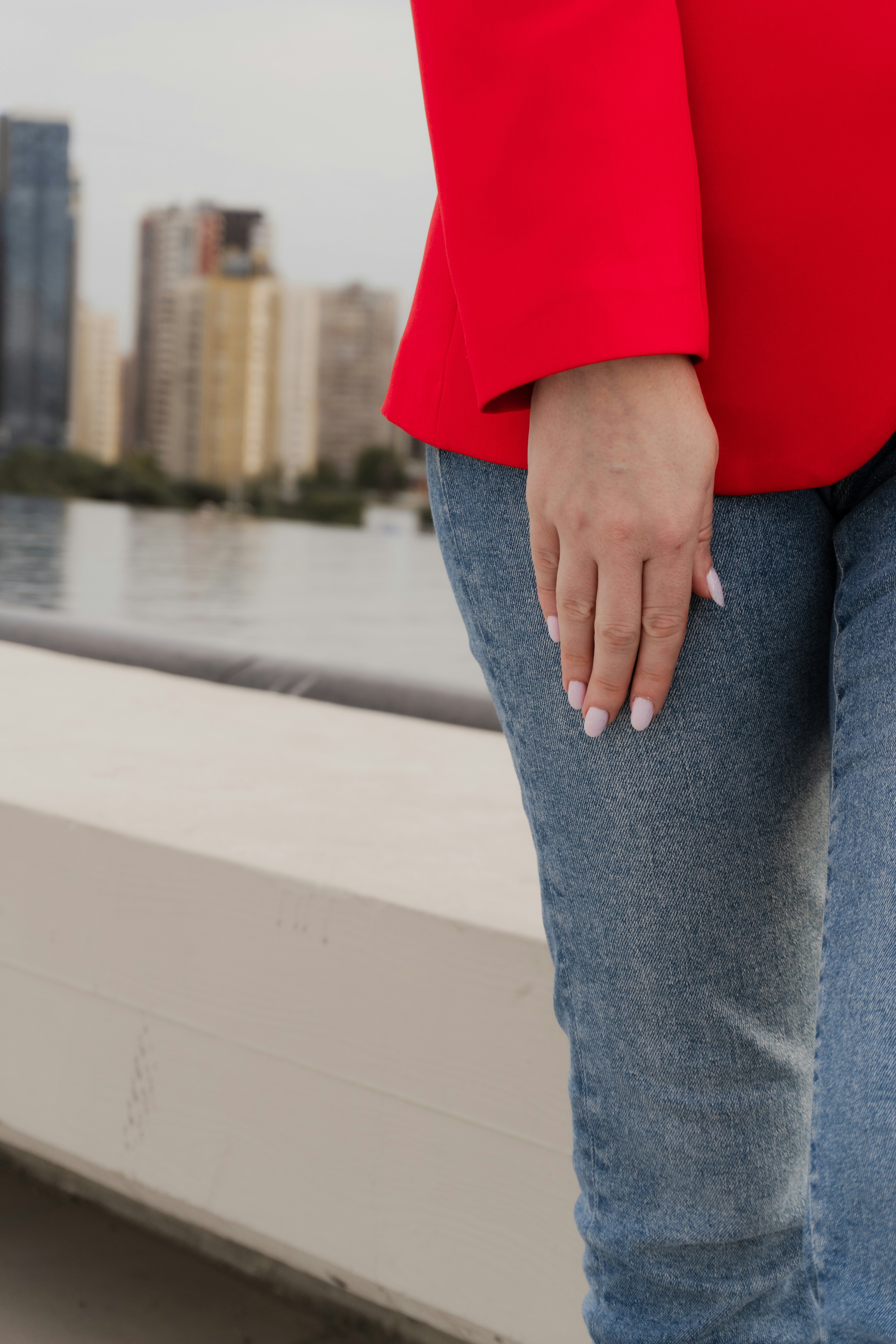 Woman in red jacket and jeans with city background