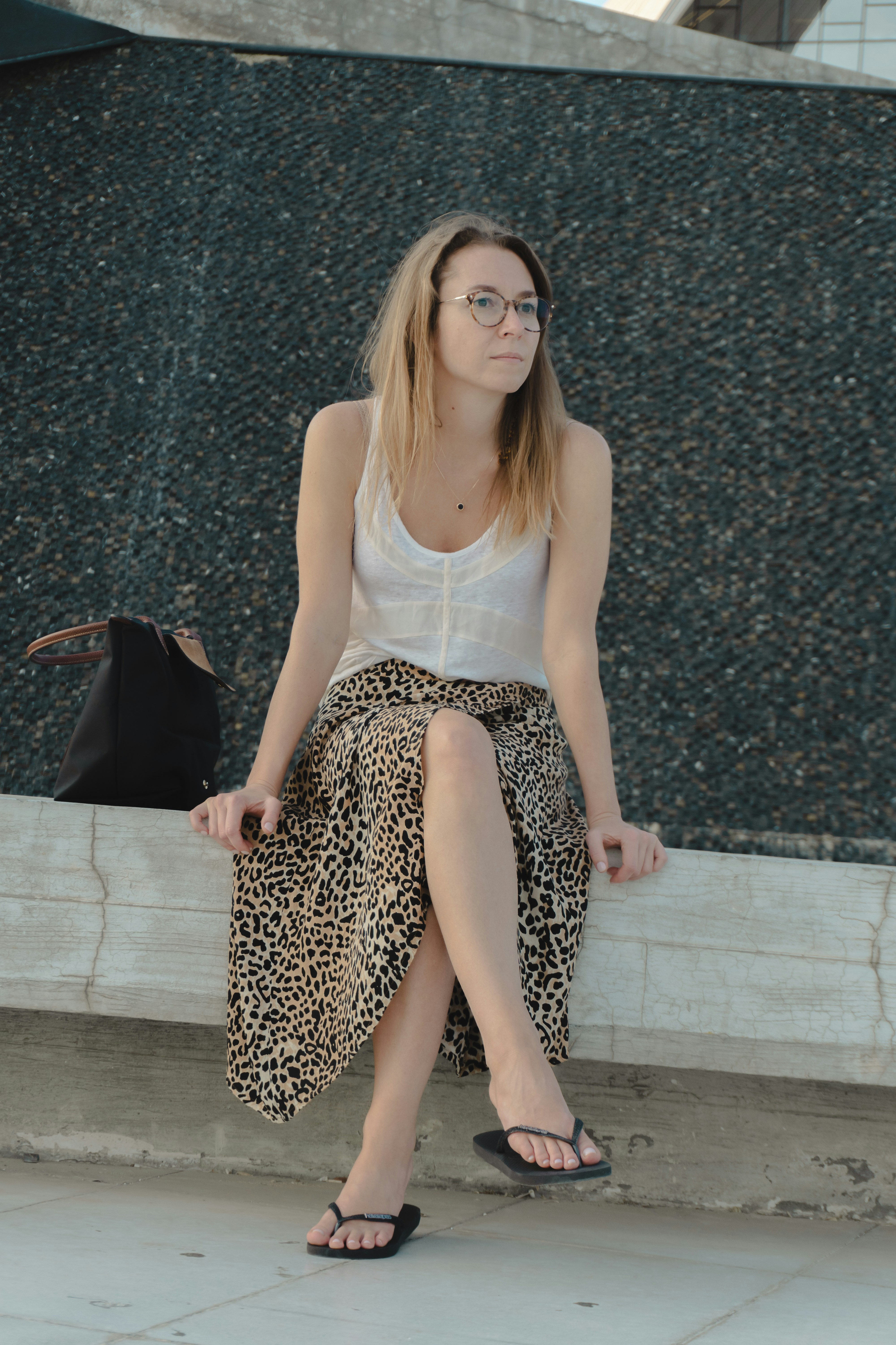 A woman in a leopard print skirt sits outdoors.