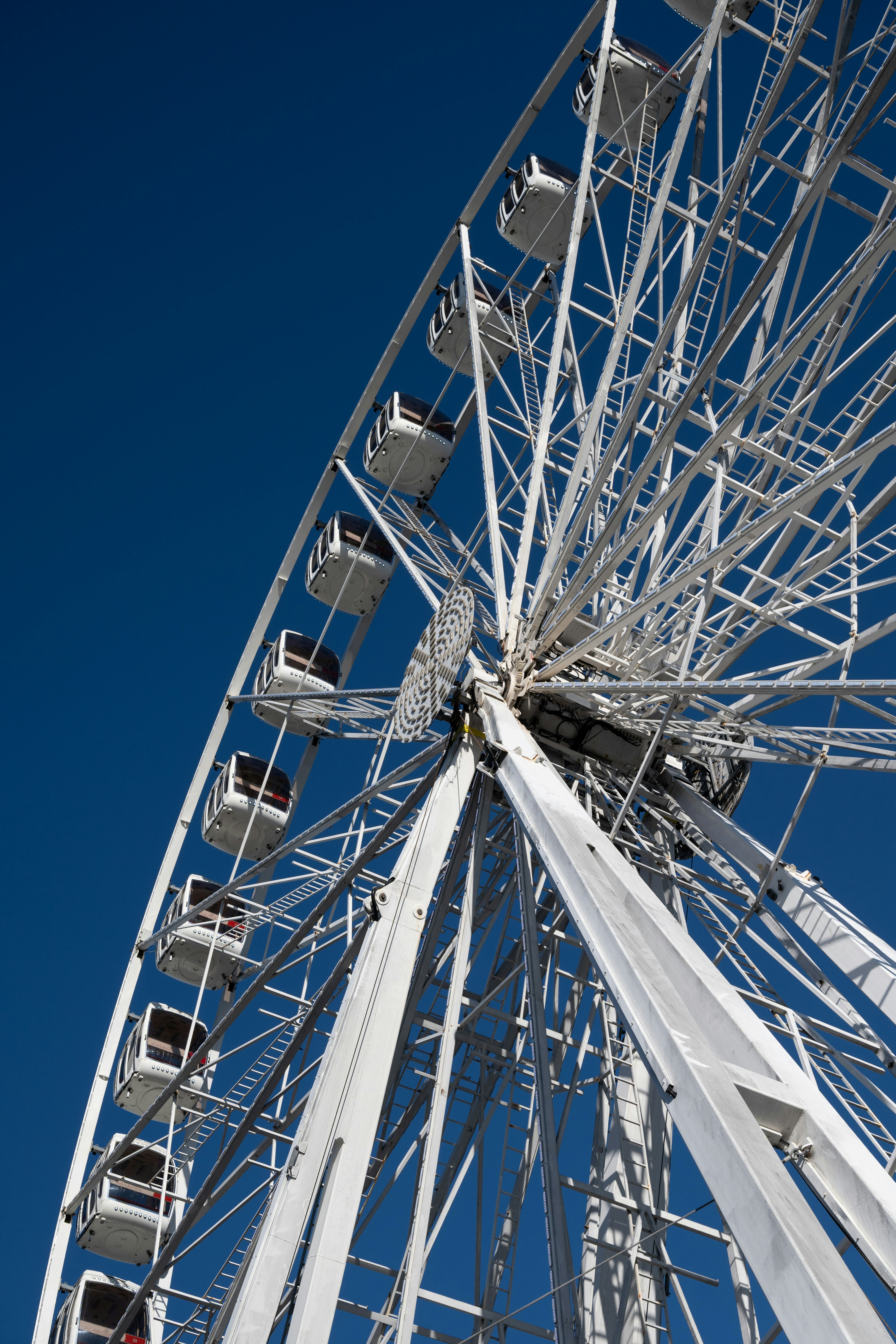 A white ferris wheel against a clear blue sky.