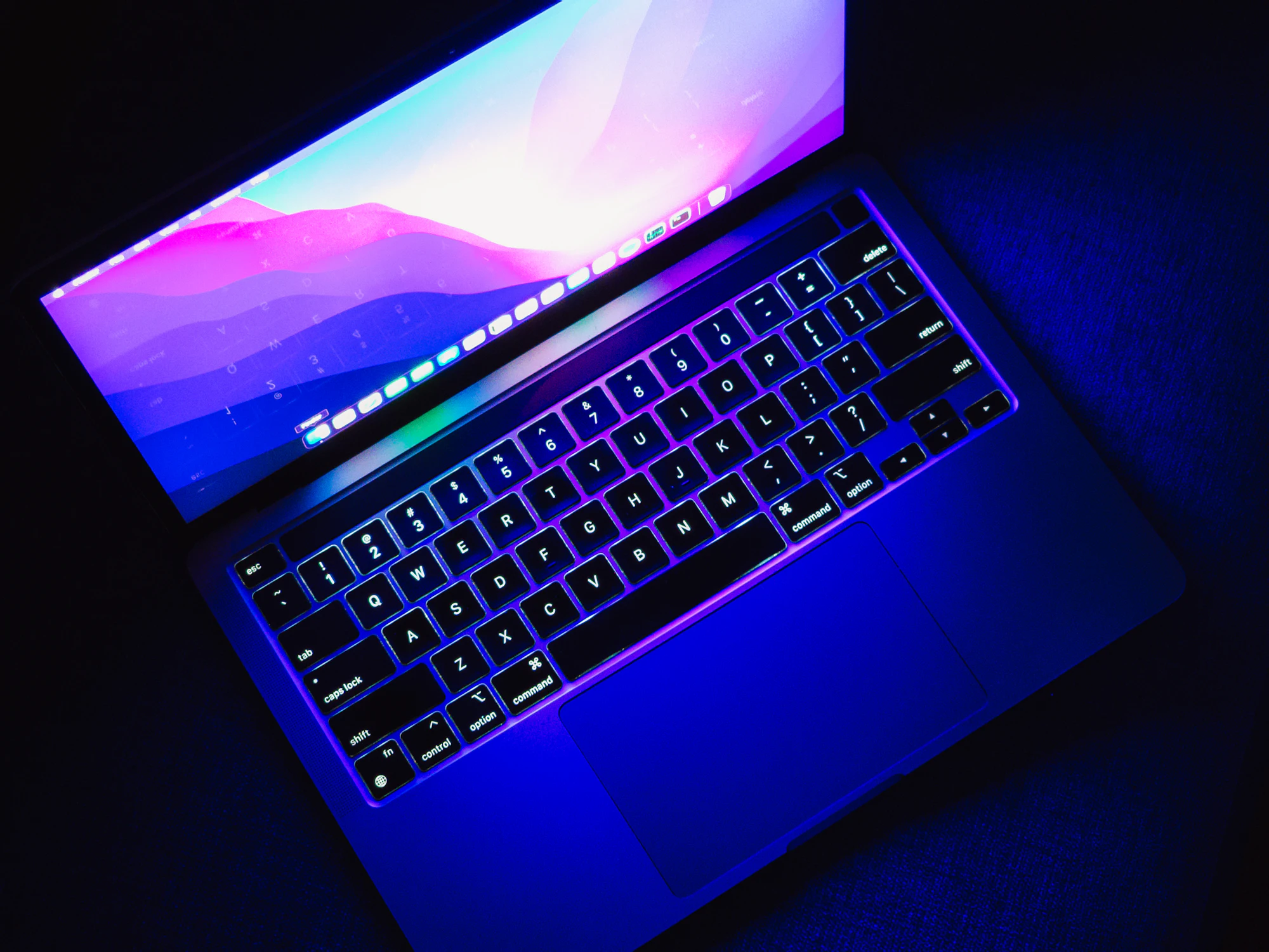 Pantalla de ordenador iluminando una sala en penumbra con un degradado de color vivo — el mismo cuidado por el detalle que pongo en cada proyecto