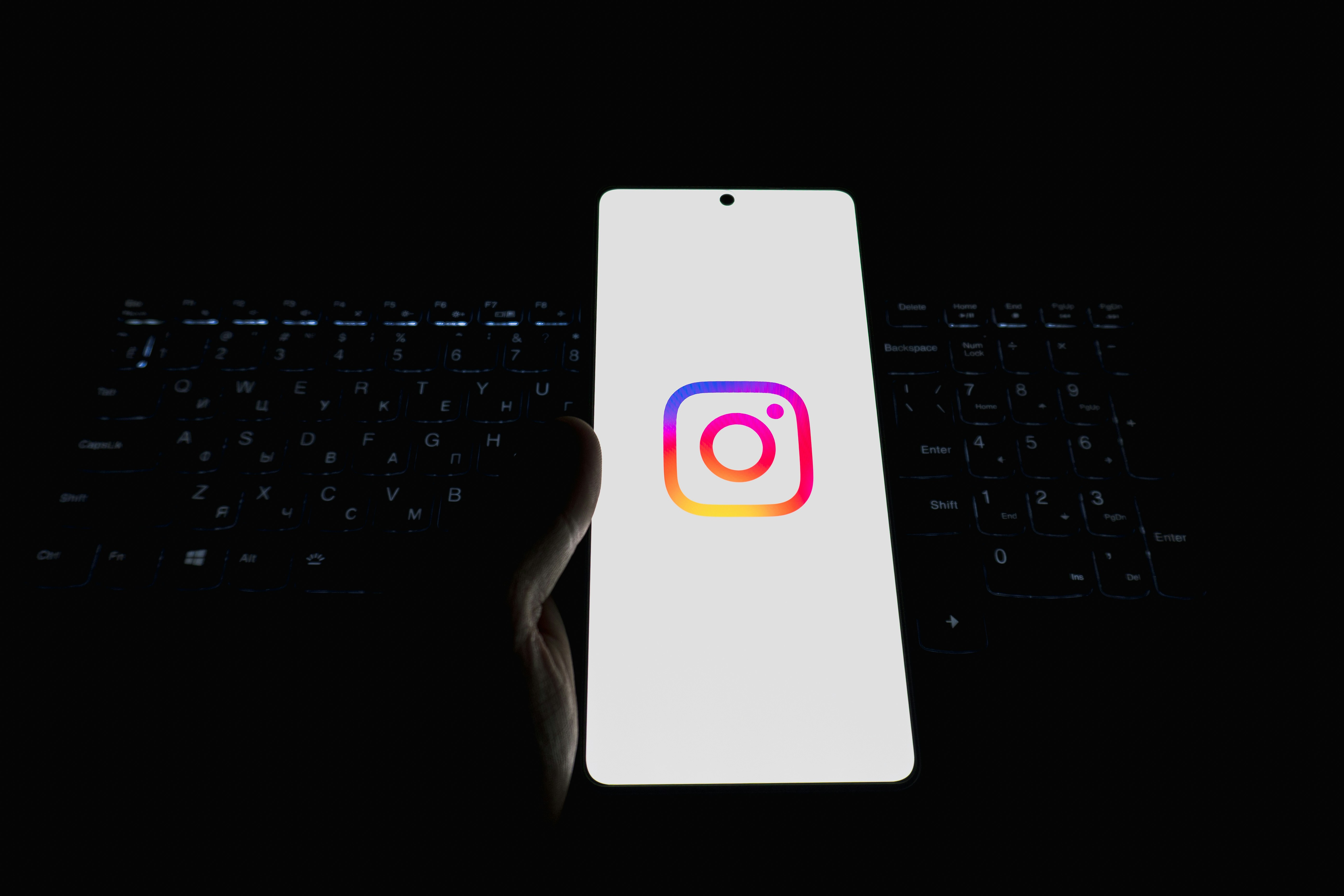 Smartphone displaying the instagram logo on a keyboard.
