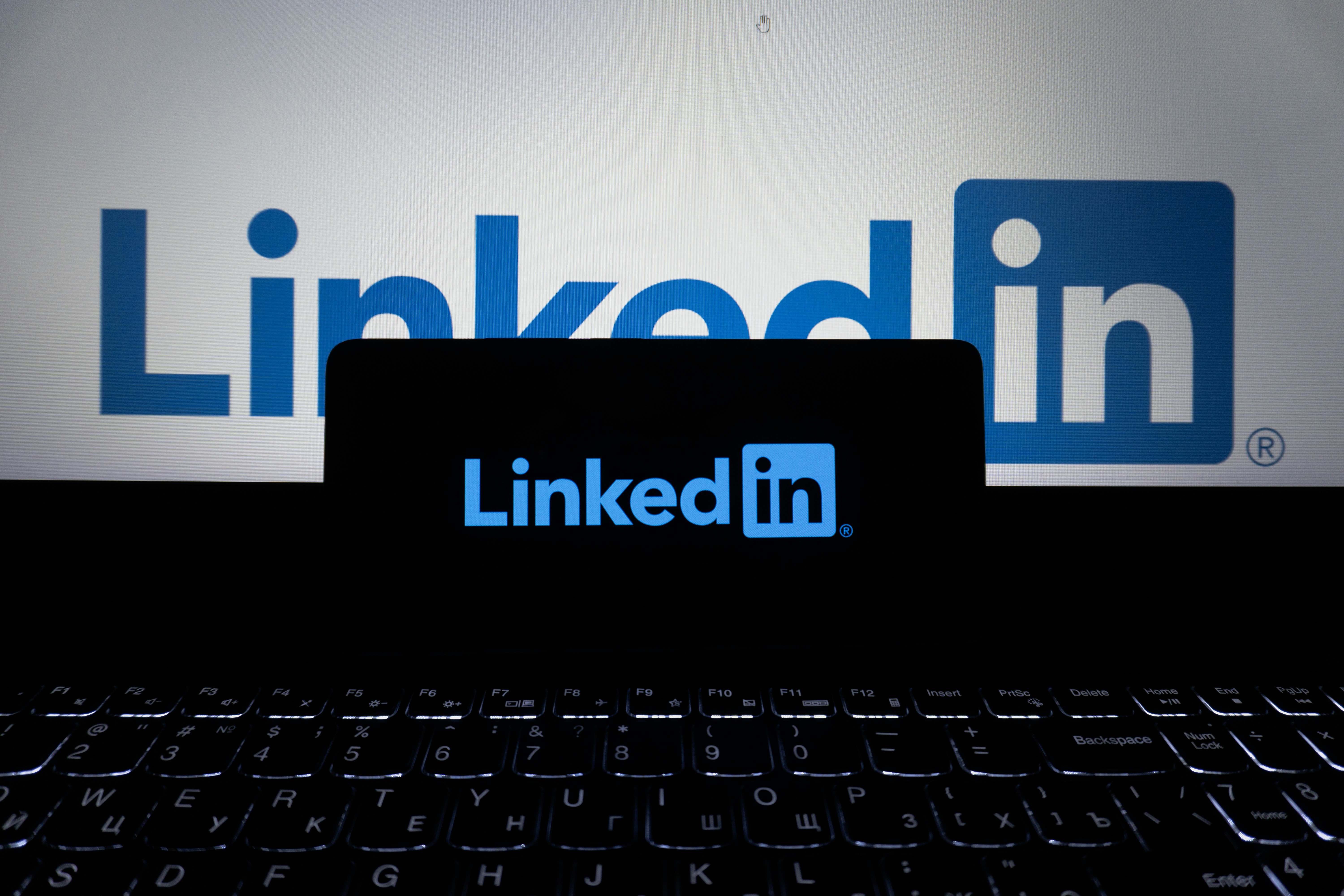 Linkedin logo displayed on a phone and laptop.