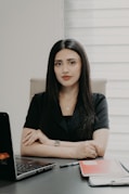 A woman in a black shirt sitting at a desk.