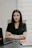 A woman in a black shirt sitting at a desk.
