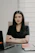 A woman in a black shirt sitting at a desk.