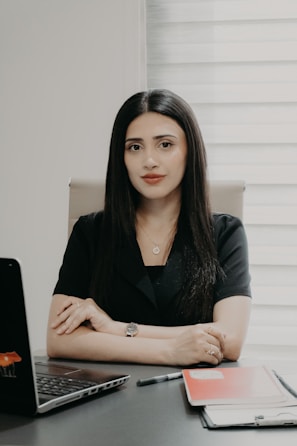 A woman in a black shirt sitting at a desk.