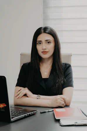 A woman in a black shirt sitting at a desk.