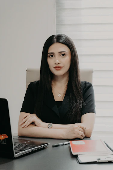 A woman in a black shirt sitting at a desk.