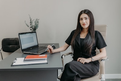 A woman sits at a desk with a laptop.