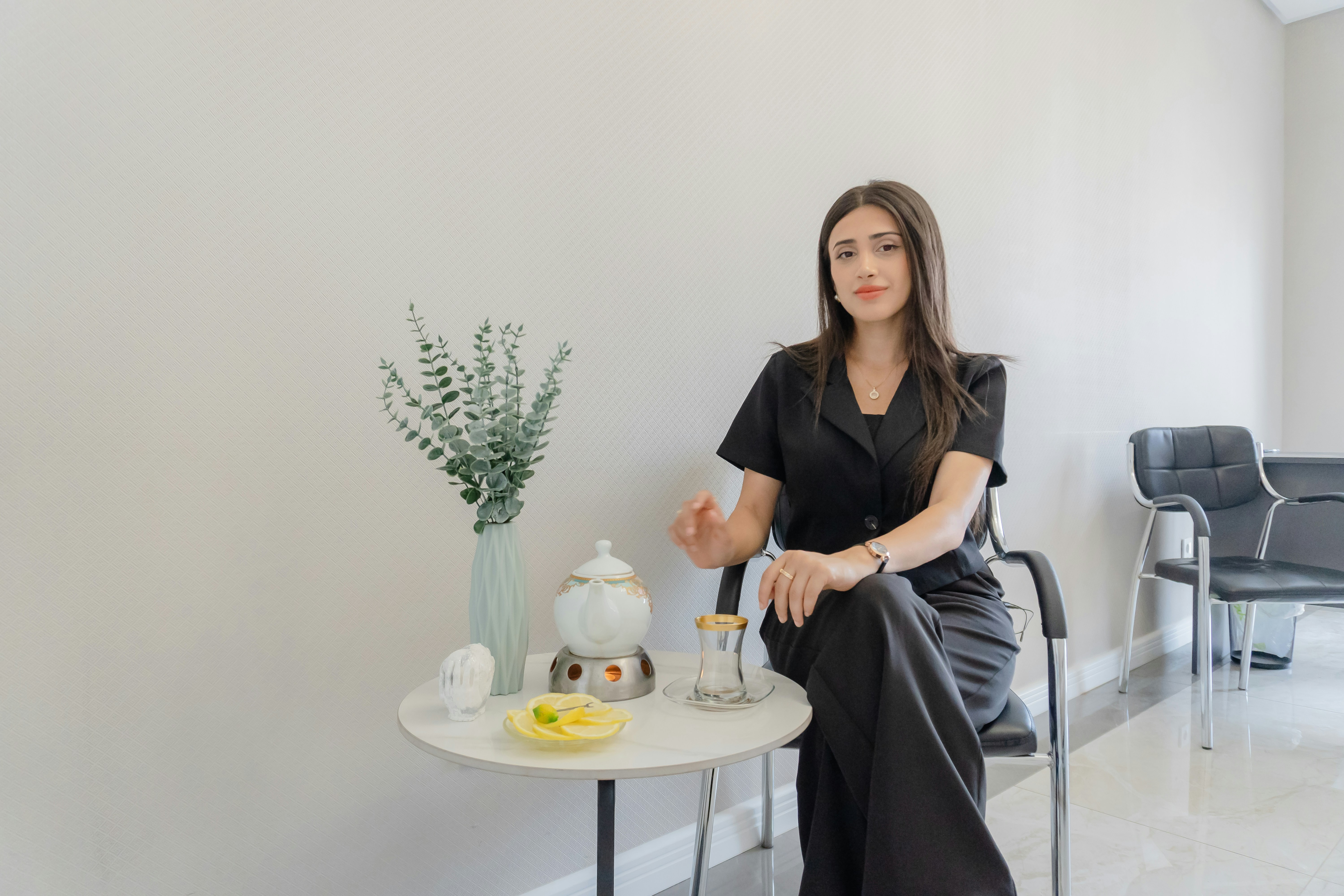 Woman in black sitting by a small table with tea