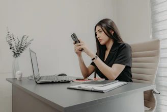 A woman using her phone at a desk