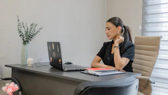 Woman working on a laptop at a desk.