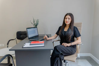 A woman sits at a desk with a laptop.