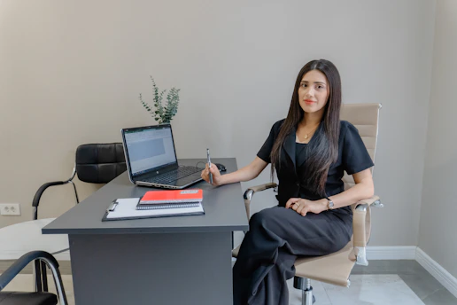 A woman sits at a desk with a laptop.