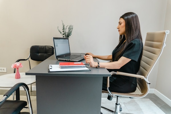 Woman working on laptop at office desk reviewing government documents