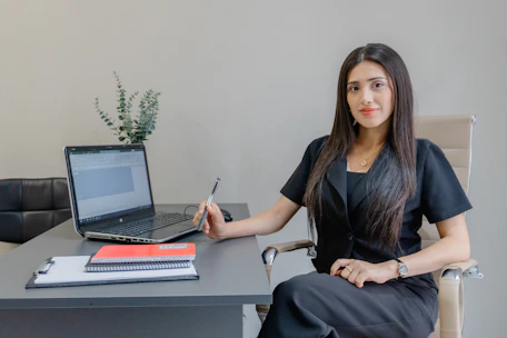 A woman sits at a desk with a laptop.