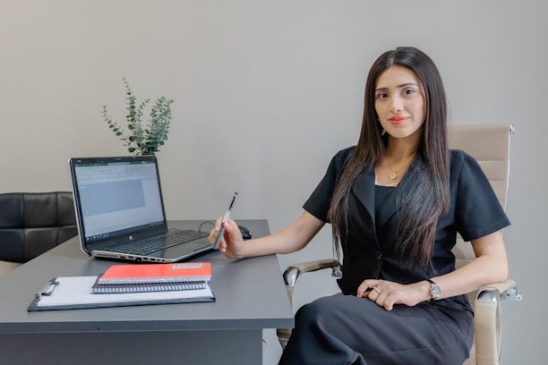 A woman sits at a desk with a laptop.