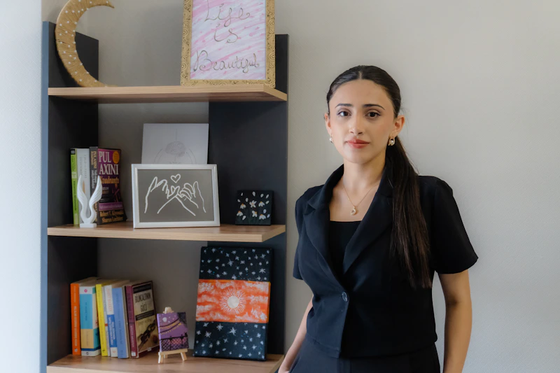 young woman in a black blazer by a bookshelf
