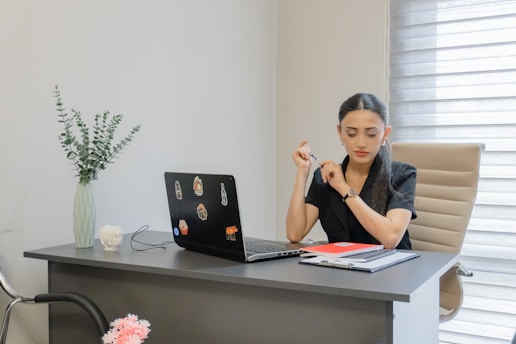 A woman works at a desk with a laptop.