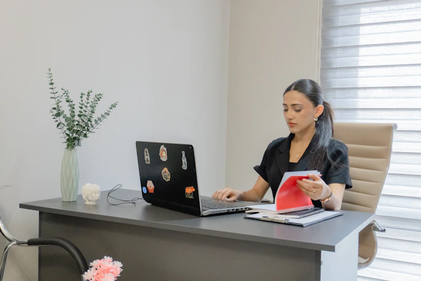 Woman working on a laptop at a desk.
