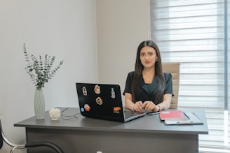 A woman sits at a desk with a laptop.