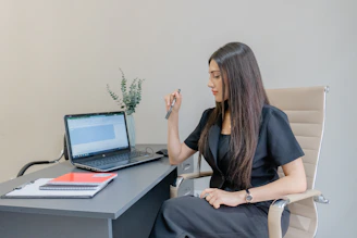 A woman working on a laptop at a desk.