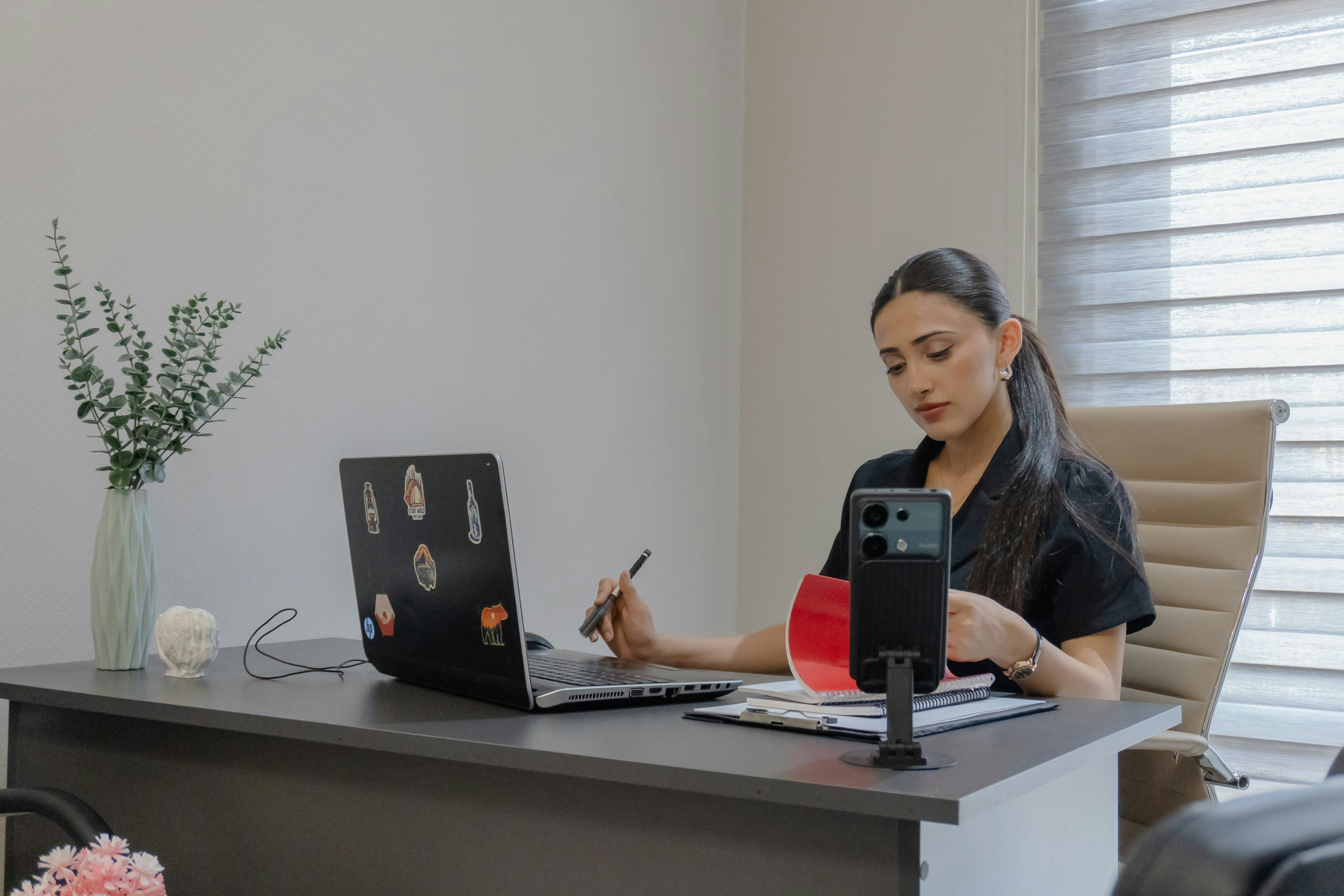 Woman working at a desk with laptop and phone.
