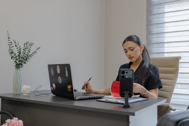 Woman working at a desk with laptop and phone.