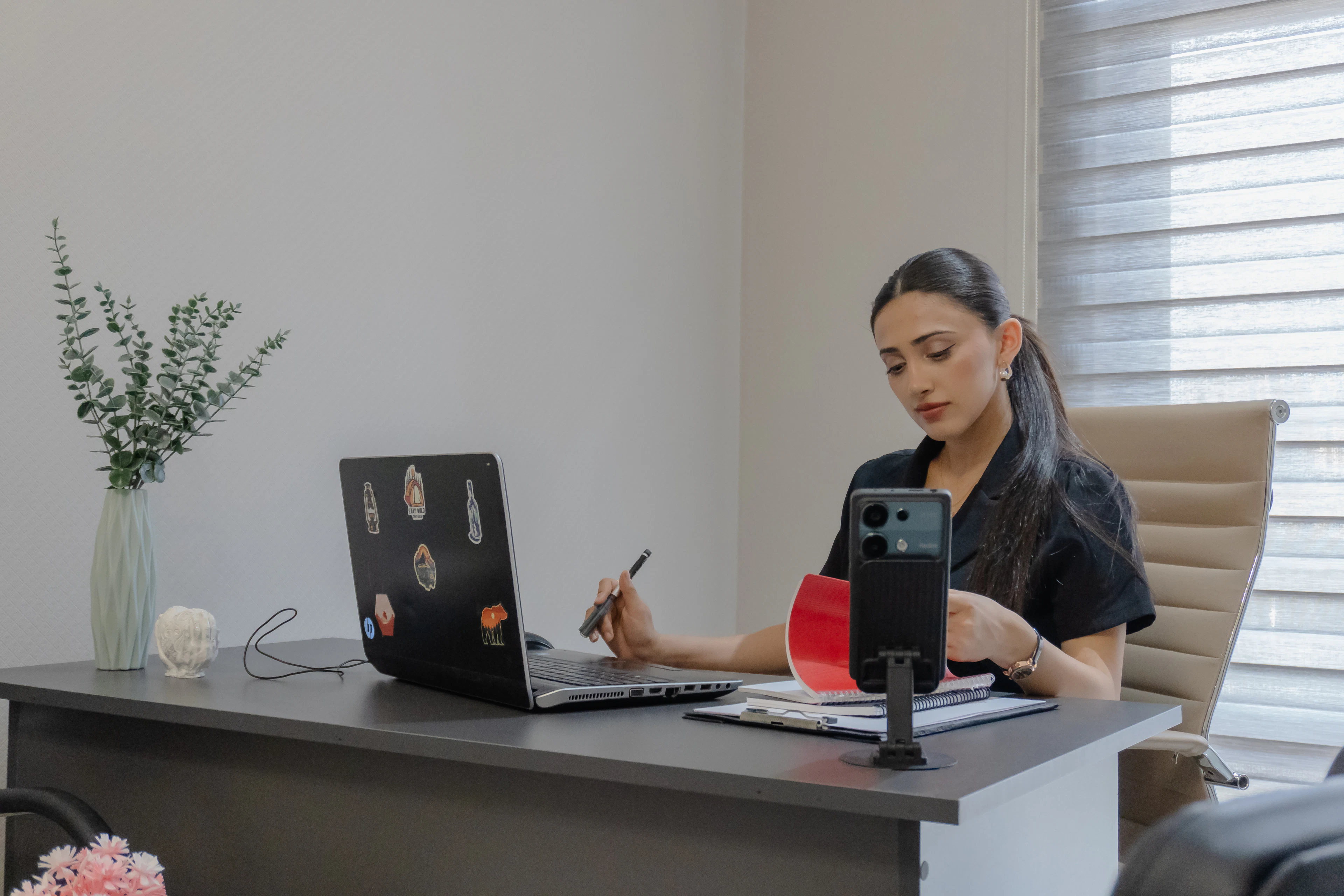 Someone at a bright desk filming content on a phone mounted to a tripod