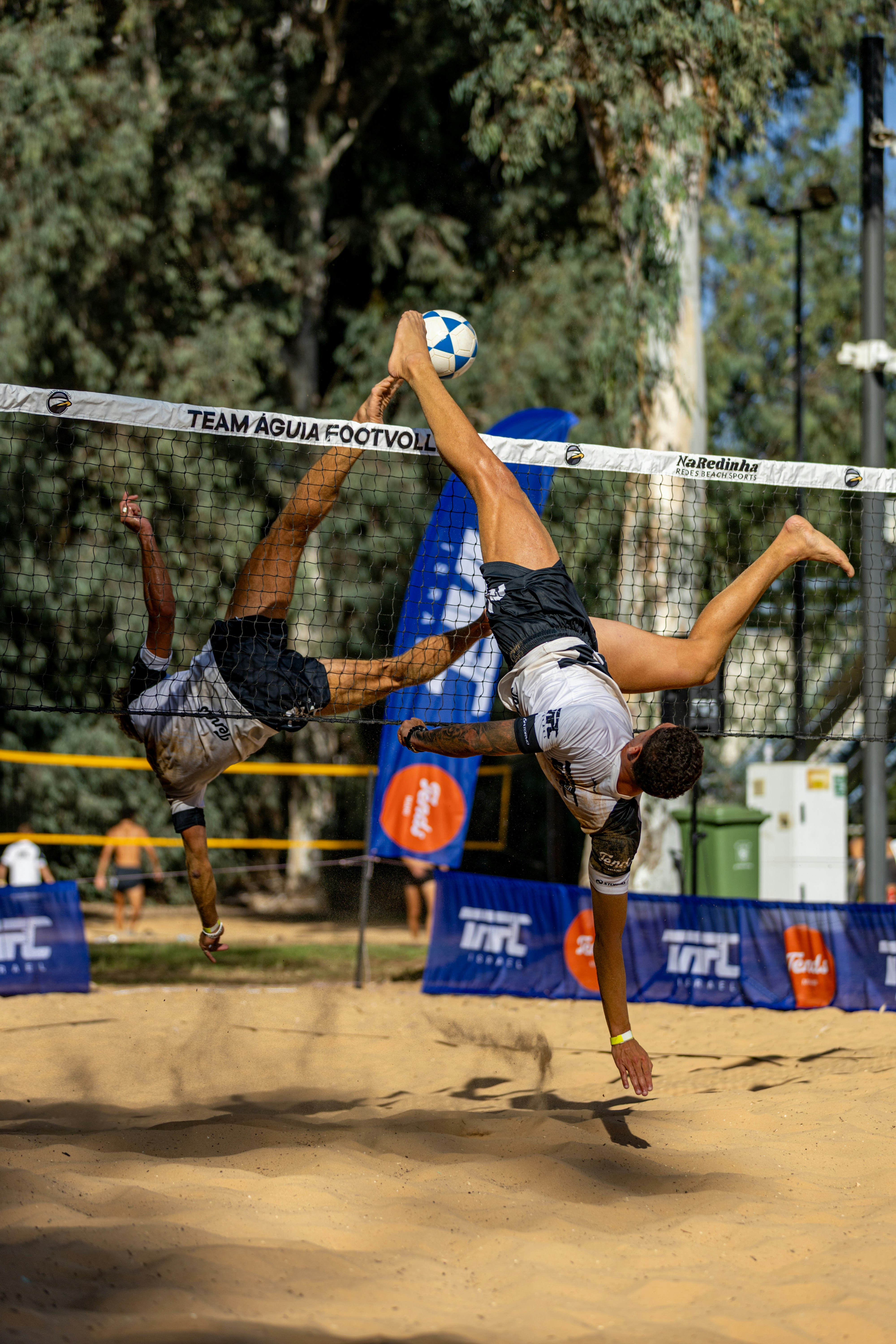 Dua atlet bermain footvolley di lapangan berpasir