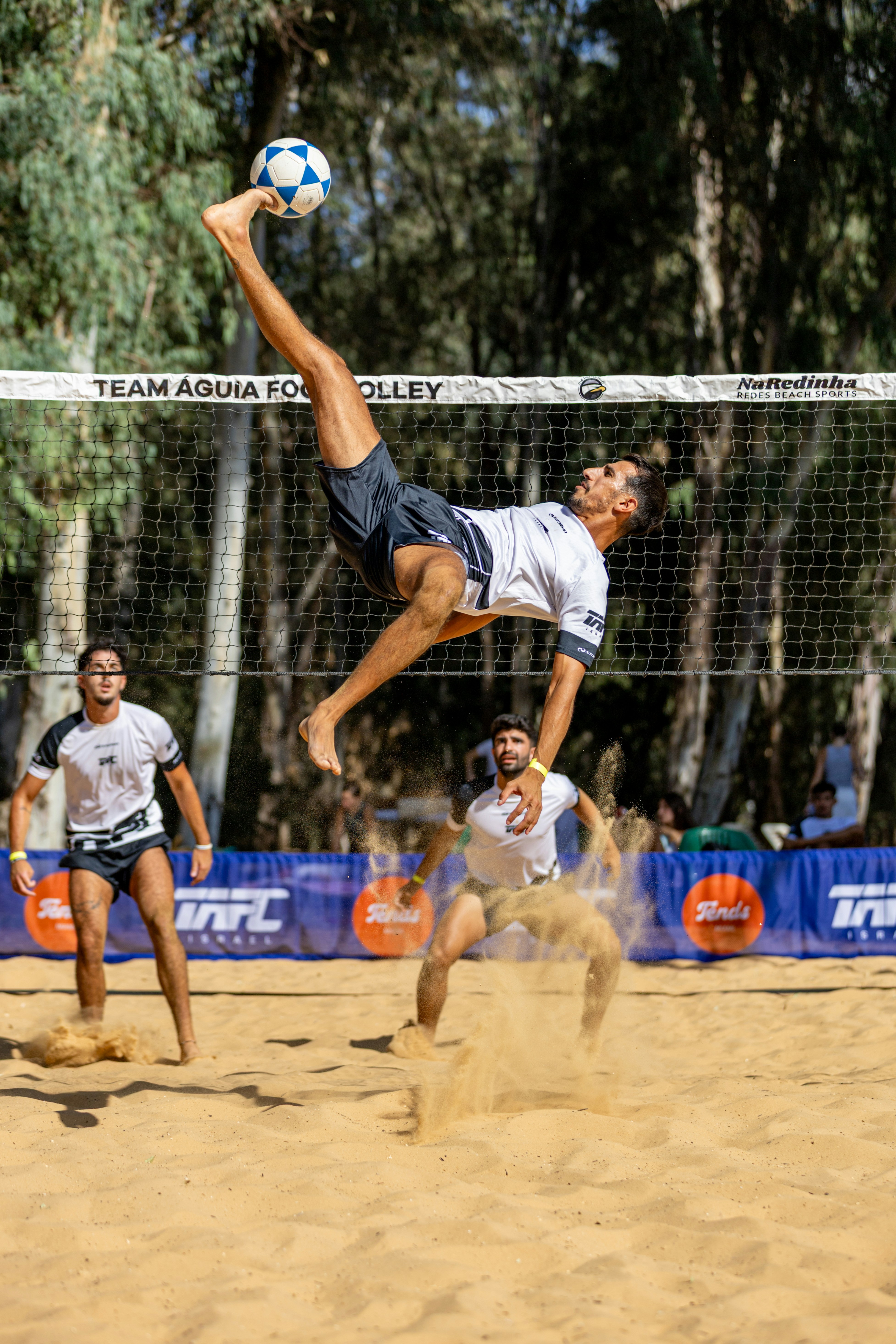 Man performs acrobatic kick during beach soccer match