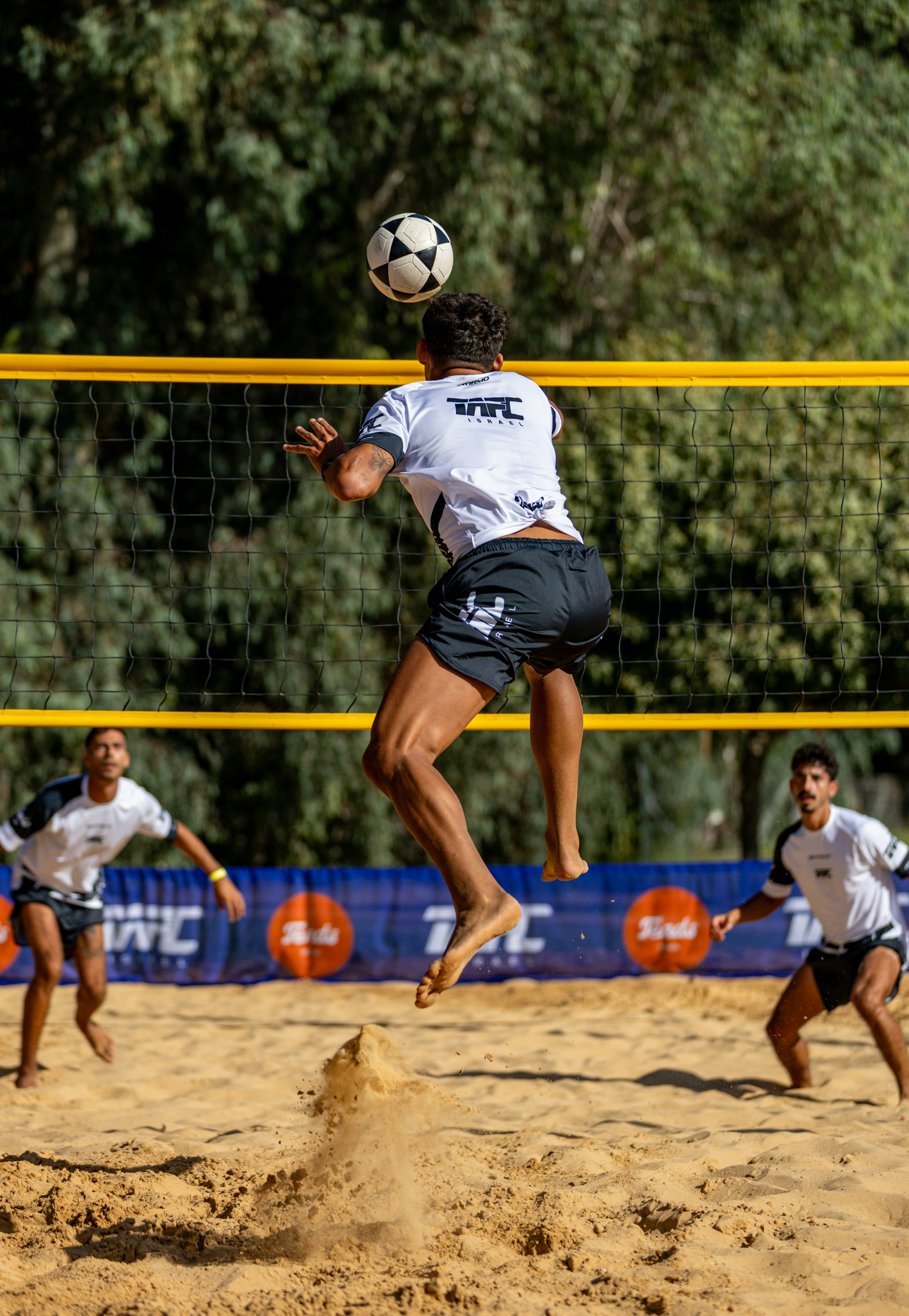Pria melompat untuk memukul bola sepak di lapangan voli pantai