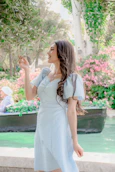 Woman in light blue dress near canal with flowers