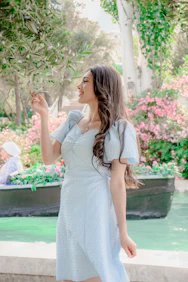 Woman in light blue dress near canal with flowers