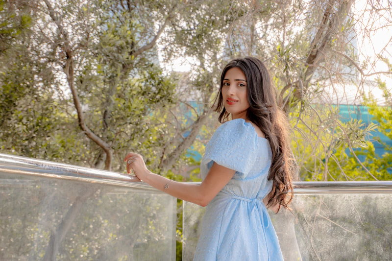 Charmante Frau im hellblauen Kleid blickt zurück