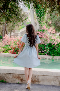 Woman in light blue dress near pink flowers