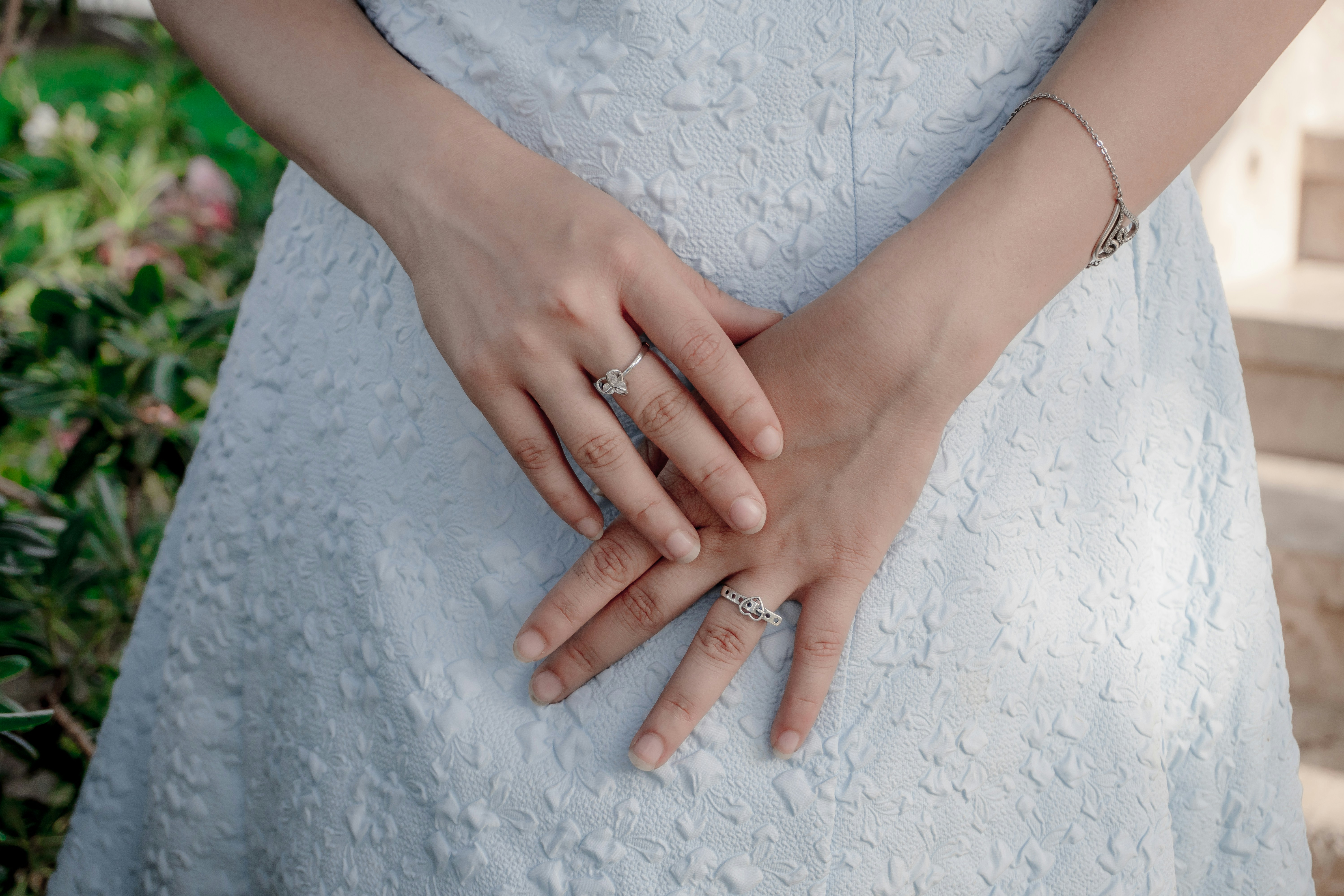 Woman's hands with rings on white dress