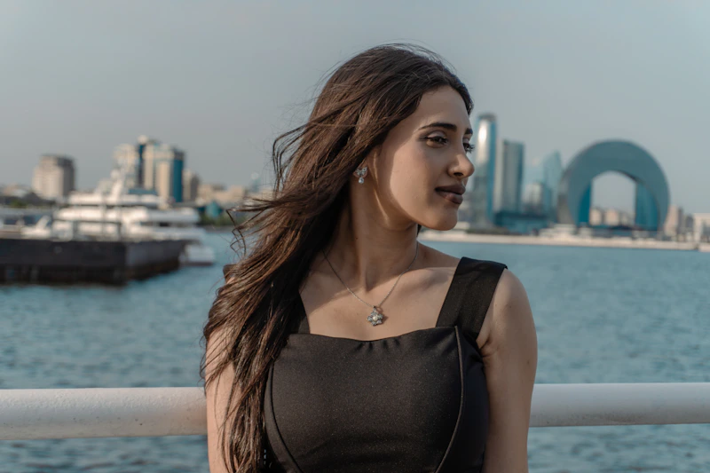 A young, elegant woman in a black dress by the water