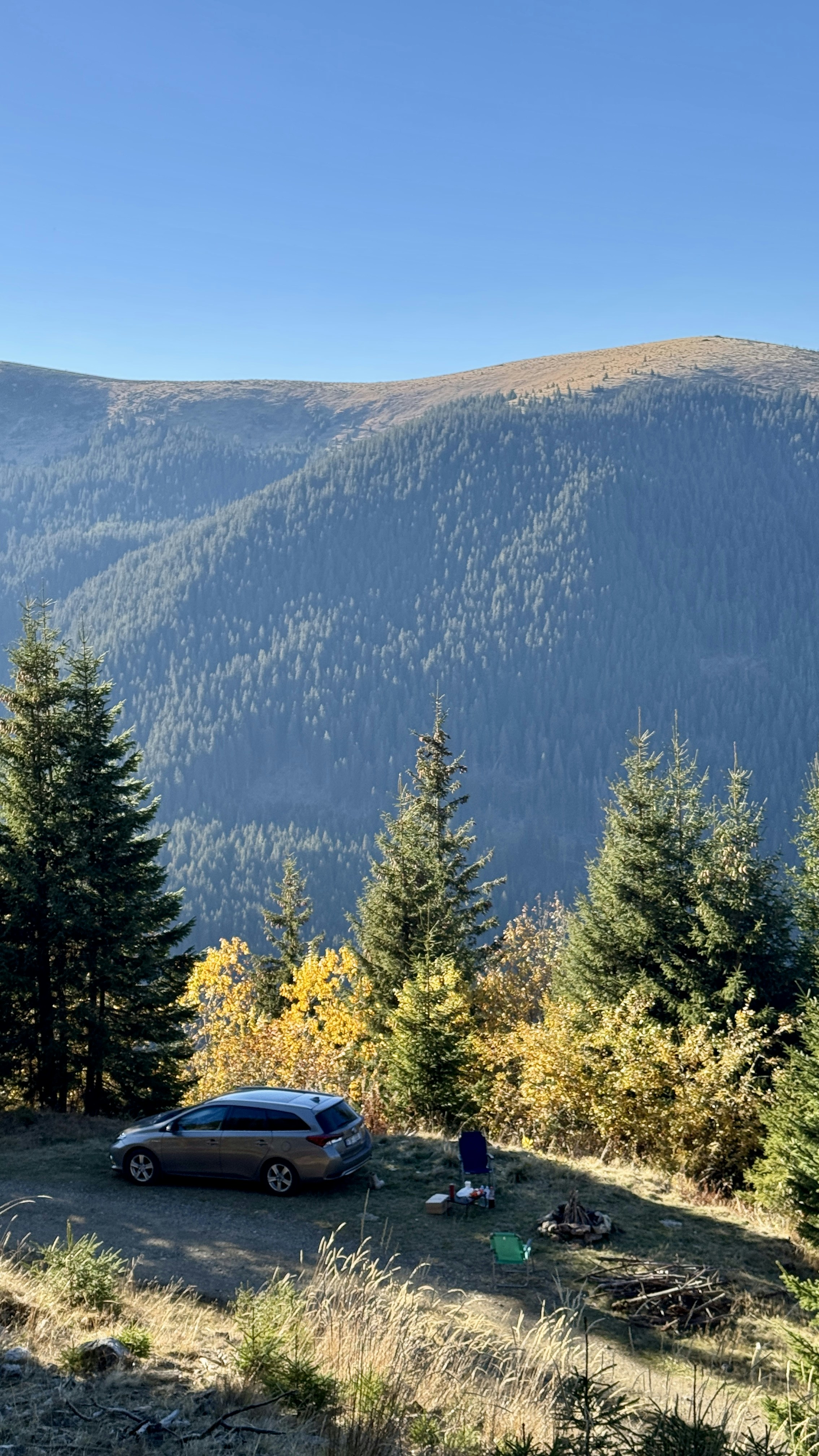Car parked on a hillside with mountain backdrop