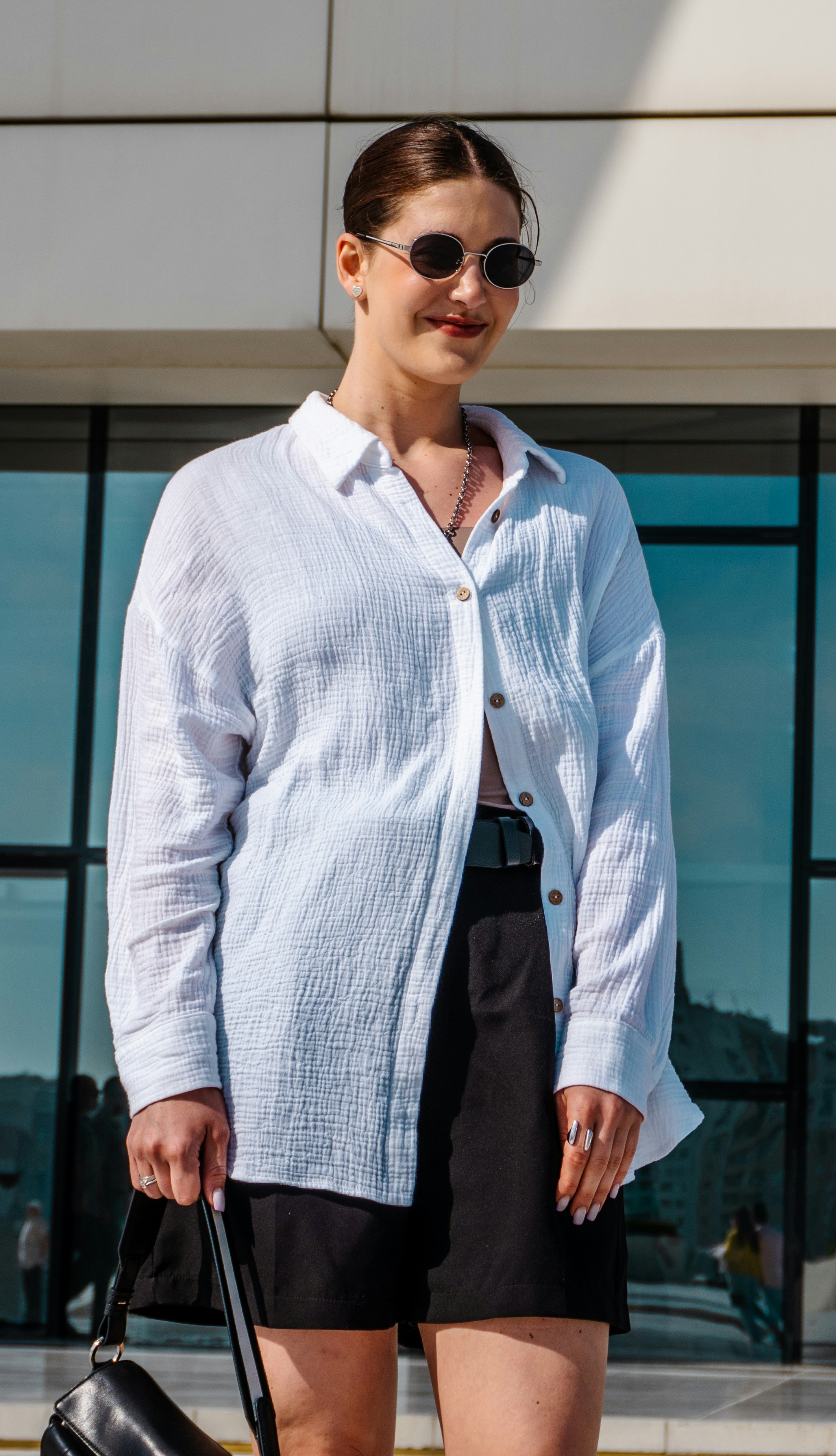 Woman in white shirt and black shorts with sunglasses