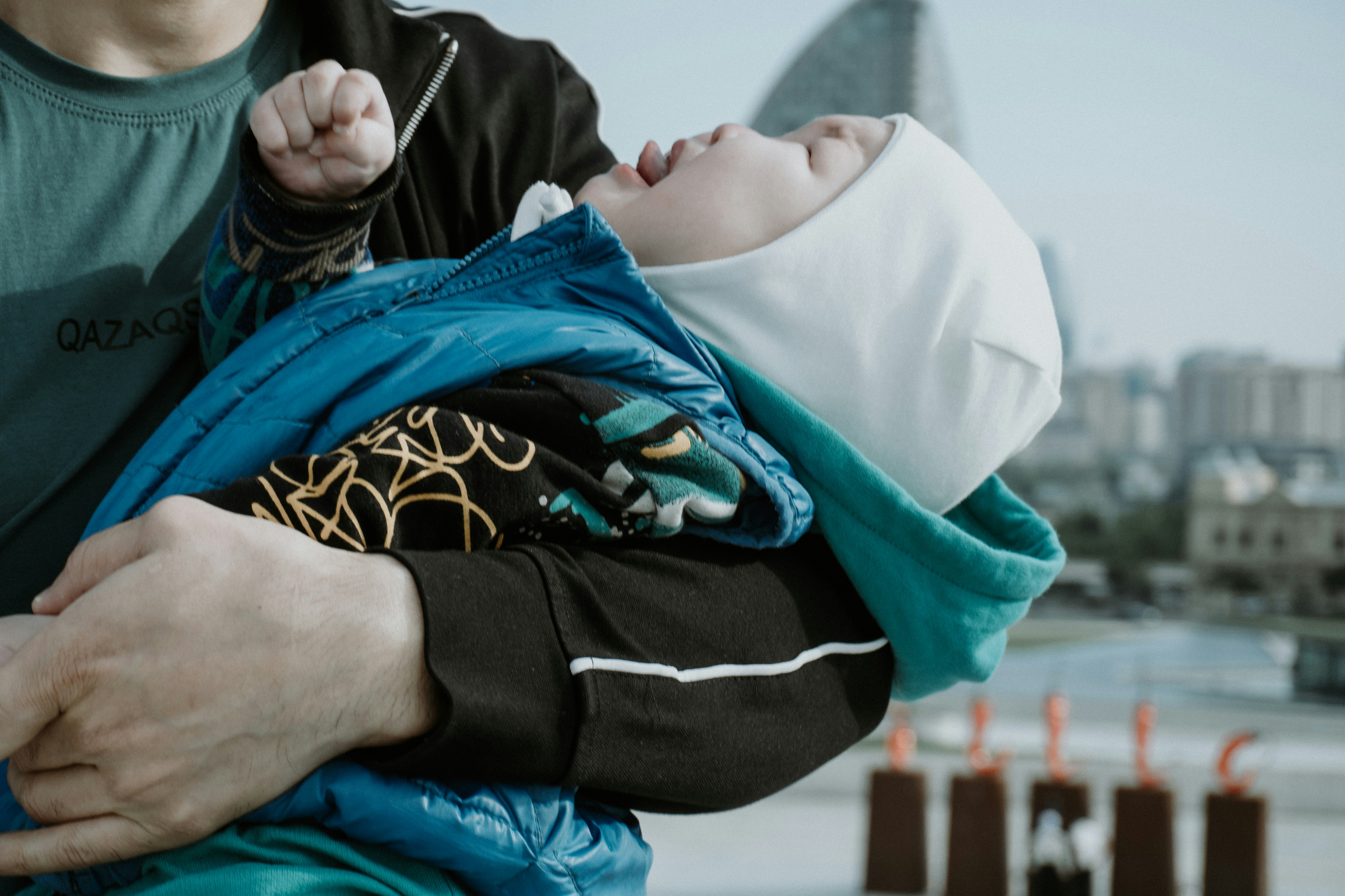 Erwachsener hält ein weinendes Baby, das in eine Decke gewickelt ist.